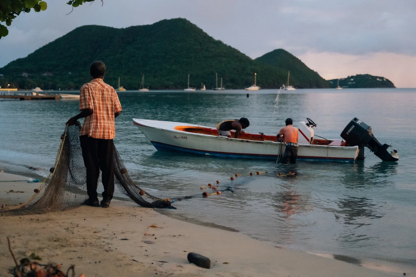 Fishermen working with a net and boat on a St. Lucia shoreline
